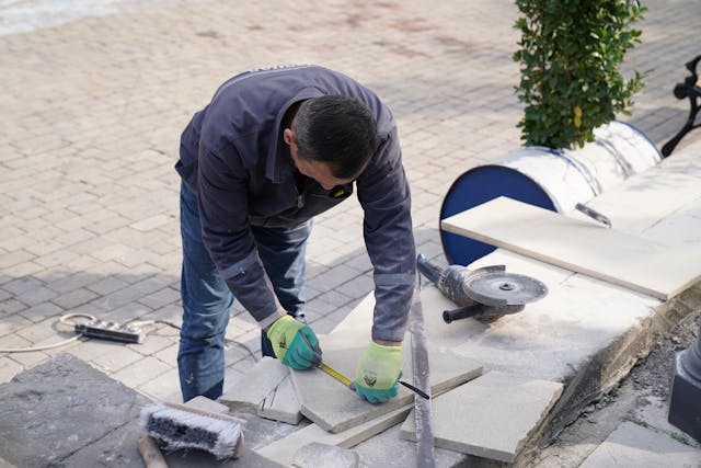 man with blue jumper and blue jeans cutting concrete slabs